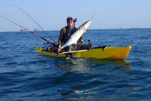 man with a caught fish on a santa cruz kayak